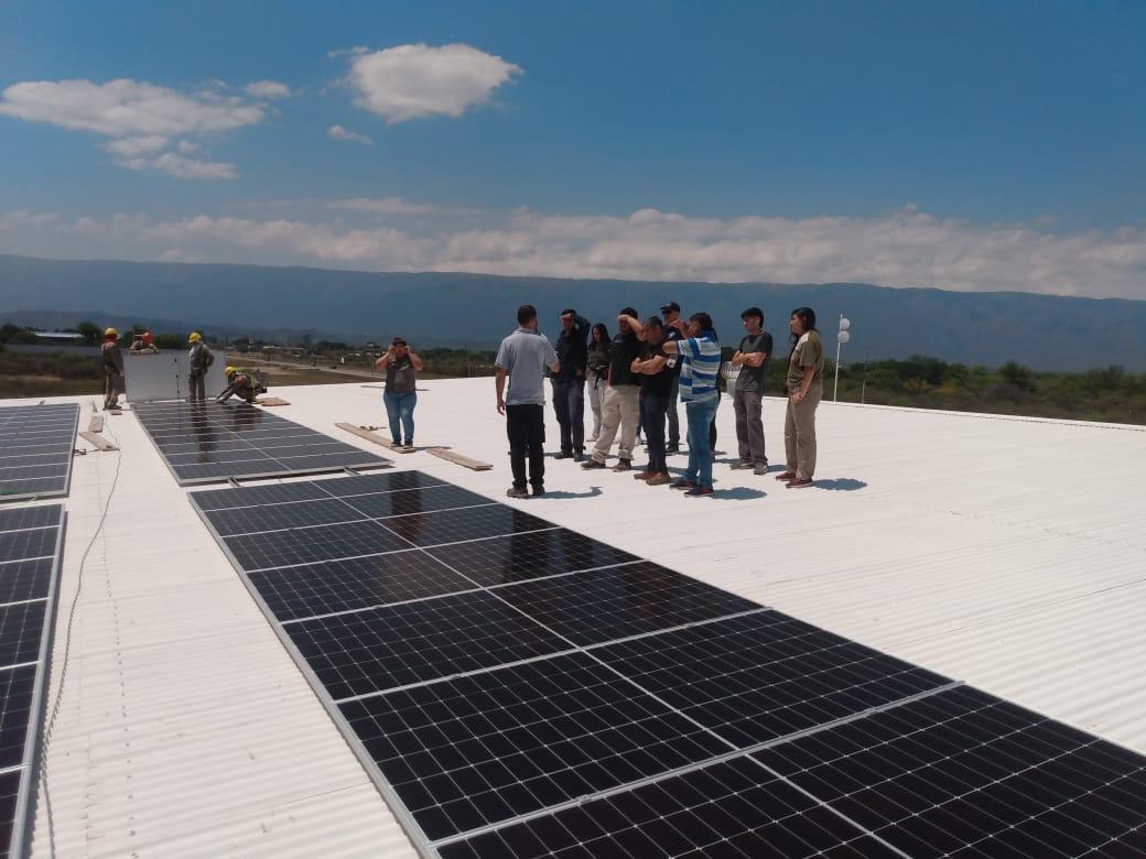 Estudiantes de Energías Renovables junto a paneles solares instalados en un techo